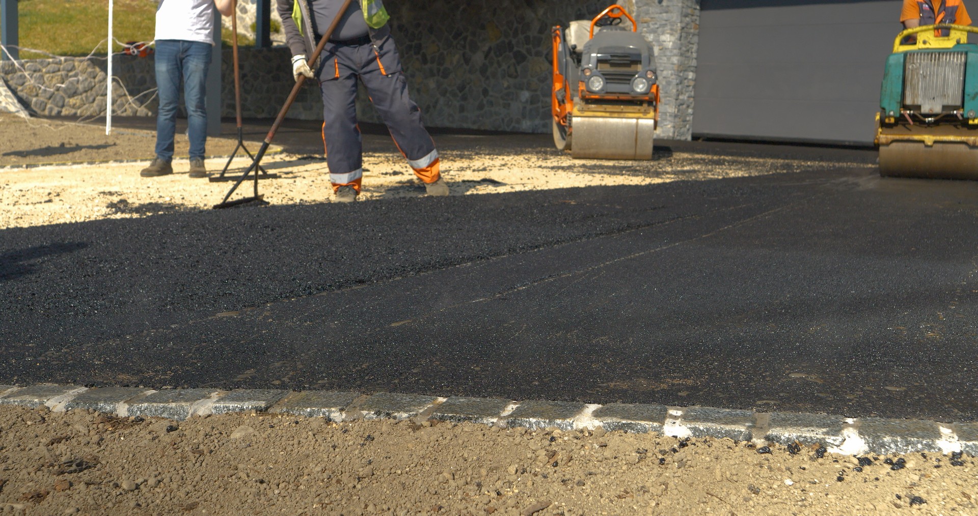 CLOSE UP: Partially asphalted and levelled fresh asphalt surface on the driveway