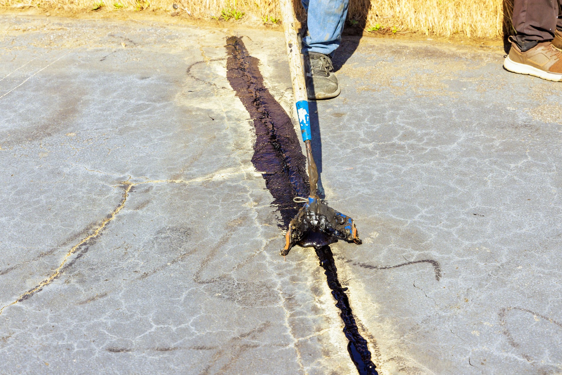Worker patcher performs coating, crack sealing, bitumen emulsion road surface restoration